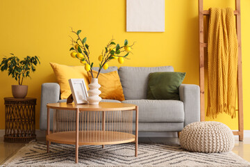 Interior of living room with sofa, tree branches and lemons in vase