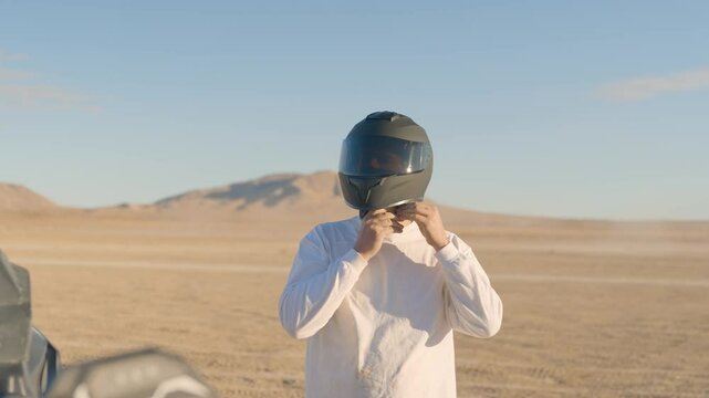 Man walking up to vehicle while buckling helmet