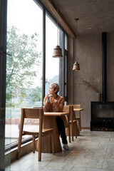 Asian fashion lady sitting alone at window table and looking away