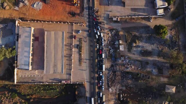 Top down view of long rows of cars in a traffic jam. The cars carefully merge and slowly drive forward. Filmed in Abuja, the capital city of Nigeria, Africa