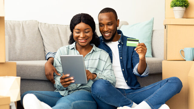 Happy African Spouses With Digital Tablet And Credit Card Choosing Furniture Online After Moving To New Apartment, Smiling Young Black Couple With Tab Computer Shopping In Internet, Free Space