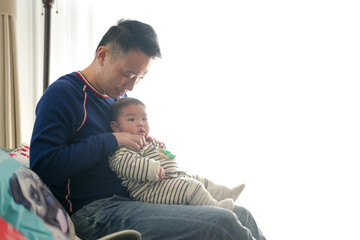 A six-month-old boy wearing Christmas clothes spends time indoors with his father from a Chinese family on a cold winter day in Pudong New Area, Shanghai, China.