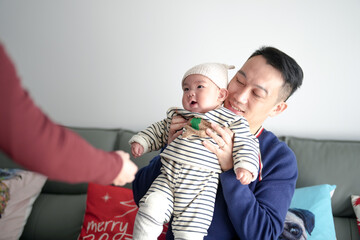 A 6-month-old boy wearing Christmas clothes spends time indoors with his father and grandmother from a Chinese family on a cold winter day in Pudong New District, Shanghai, China.