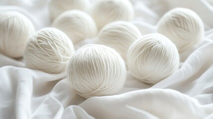Fototapeta premium Neatly arranged white yarn balls on a soft white fabric