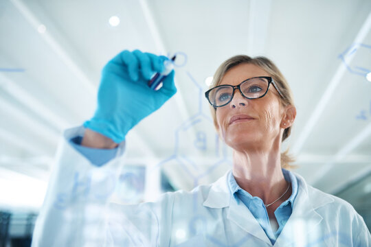 Woman, science and formula on glass board at laboratory for planning, strategy and ideas on medical research. Mature person, scientist and investigation or study with notes for clinical or drug trial