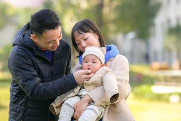 A 6-month-old boy plays with his mother and father, a Chinese family, on a cold winter day in a...