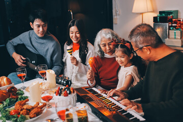 Multi-Generation Family Celebrate Christmas At Home Wearing Santa Hats And Antlers Opening Presents