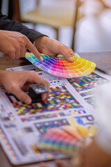 Team graphic designer checking print quality of media graphics proof print and color guides in...