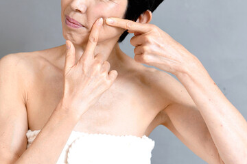 頬に指を指す笑顔の中年のアジア人女性