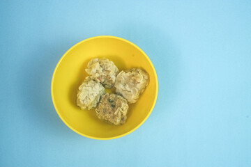 Traditional Chinese steamed dumplings, Dim Sum in yellow bowl on bright blue surface with copy space