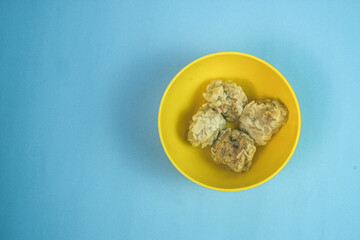 Traditional Chinese steamed dumplings, Dim Sum in yellow bowl on bright blue surface with copy space