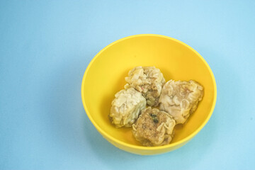 Traditional Chinese steamed dumplings, Dim Sum in yellow bowl on bright blue surface