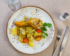 Delicious baked chicken legs with garnish of boiled potatoes on plate