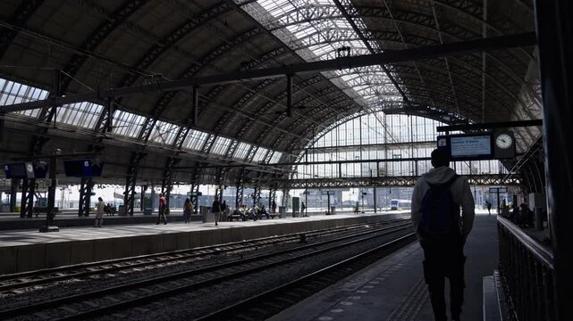 Pedestrian walks along platform at train station to await his train