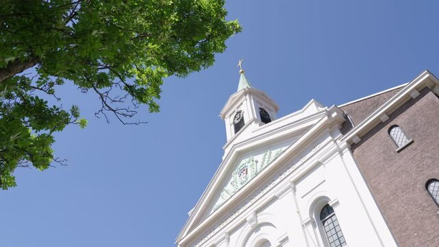  Stunning church steeple rises against bright blue sky and leafy trees