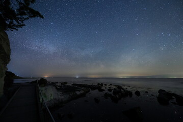 海沿いの遊歩道から見る水面の星と能登半島の星空