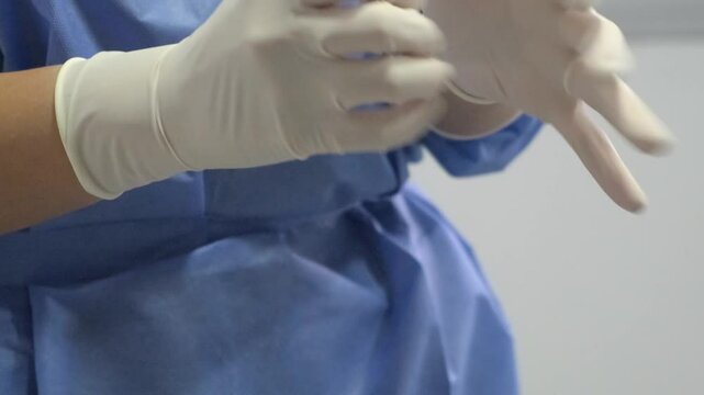 Medical professional preparing by donning sterile gloves in a clinical setting