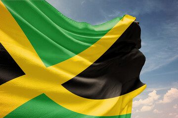 Waving flag of Jamaica in blue sky. Jamaica flag on pole for Independence Day. The symbol of the state on wavy fabric.
