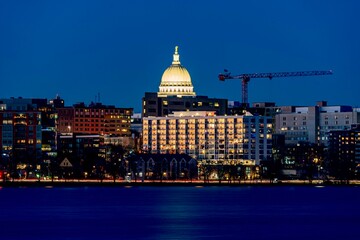 Obraz premium Downtown Madison, WI and the Wisconsin State Capitol Building behind Lake Monona at Twilight