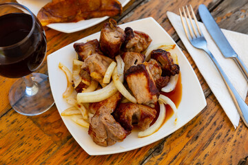 Oriental grilled pork meat shashlik with sliced onion rings on a plate