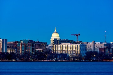 Naklejka premium Downtown Madison, WI and the Wisconsin State Capitol Building behind Lake Monona at Twilight