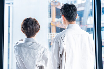 Obraz premium 工事現場をバックに窓の外を見つめる男女