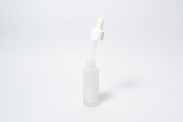 White dropper glass bottle with white liquid inside on isolated white background