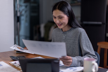 Obraz premium freelancer asian woman writing on a notebook while working on laptop computer in home office 