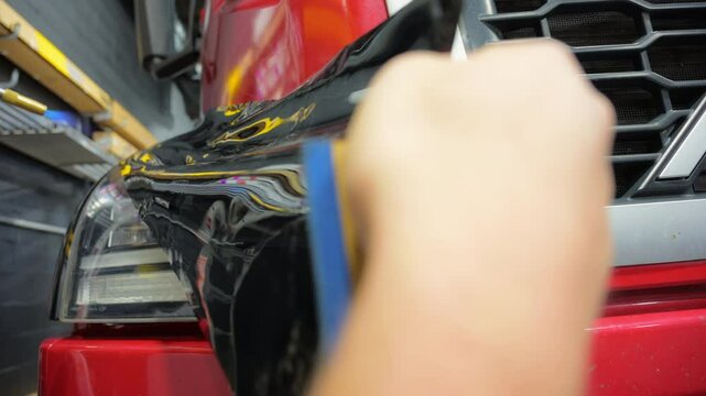 Process of applying a PPF film with a heating to a red truck. Close up footage of applying a film on a car. 