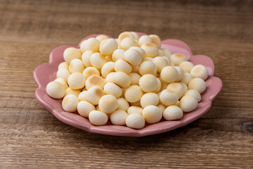 木目のテーブルに置かれたピンク皿とたっぷりのたまごボーロ