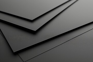 Black paper sheets stacked on a dark surface in a minimalist setting, highlighting texture and contrast