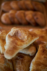 Fresh baked goods: samsa with meat, sprinkled white sesame seeds lies in heap on wooden plate. Asian food, Traditional eastern cuisine Tajikistan, Uzbekistan, Kyrgyzstan. triangular puff pastry samosa