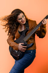 Musician playing electric guitar with passion and energy on orange background