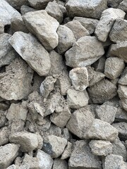 A close-up view of rough, jagged concrete rubble. The pieces are irregularly shaped with visible...