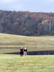 Two women are walking in a field with a lake in the background