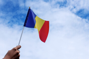 Raised Hands Holding Rumania National Flag Waving in Beautiful Clouds.
