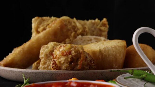 close up on dipping combro in the spicy sauce with a black background. Combro is a typical Sundanese fried food. Comro is made from grated cassava which is shaped round or oval and filled with oncom
