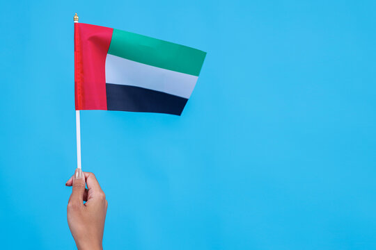 Raised Hands Holding UAE National Flag Isolated on Blue Background