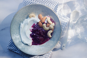 homemade greek style yogurt with mix berry jam, almond and cashew nut in ceramic bowl.