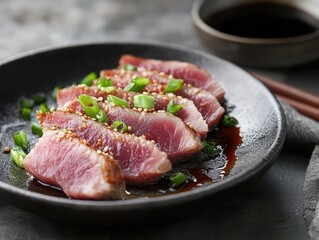 Sliced meat garnished with green onions and sesame on a dark plate, served with sauce.