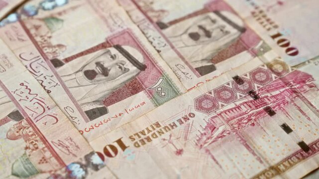 Saudi arabian banknotes featuring 100 riyals in various arrangements with intricate designs and king's portrait, highlighting details and currency.