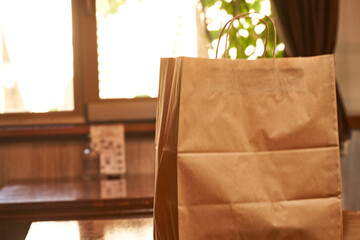 A hand with a paper shopping bag in a cafe, close-up. Food delivery service.   