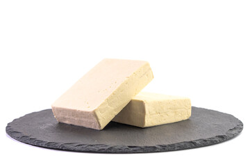 Two pieces of raw tofu on a gray plate isolated on white background.Vegan food ingredient in Asian cuisine, Plant based diet