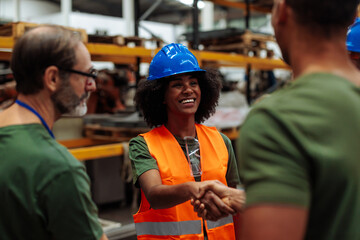 Female engineer shaking hands with supervisor in warehouse