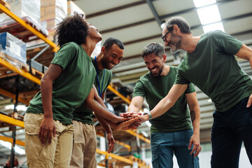 Warehouse workers joining hands in teamwork and collaboration, celebrating success