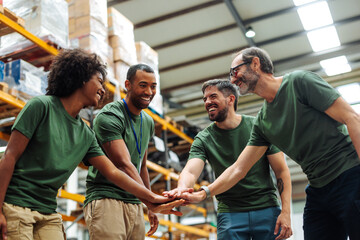 Warehouse workers joining hands for teamwork and success