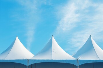 A white tent with three peaks is set up in a blue sky