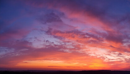 Obraz premium sunset cloudscape Panoramic with rich purple and pink tones blending into orange at horizon, tranquil evening sky view, natural dusk setting, soft wispy cloud formation, twilight backdrop