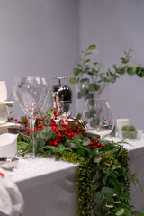 Wedding table decoration with red berries and green plants in a restaurant. Restaurant christmas decoration.