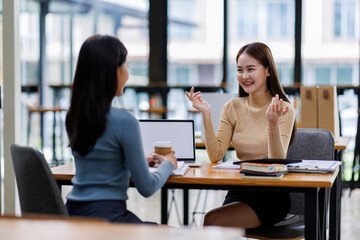 Two asian female creative agency casual meeting discussion working with laptop, analyze planning and financial statistics and investment market at office.
